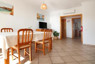 a dining room with a table and chairs and a television at Apt Baleeira Sol in Albufeira