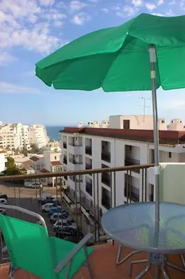 a table and chairs with an umbrella on a balcony at Sunny Apartment Close to the Beach in Albufeira