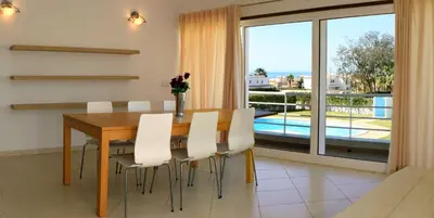 a dining room with a wooden table and white chairs at Villas Oceano in Albufeira