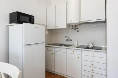 a kitchen with white cabinets and a white refrigerator at Maresia - Front beach - Quarteira in Vilamoura