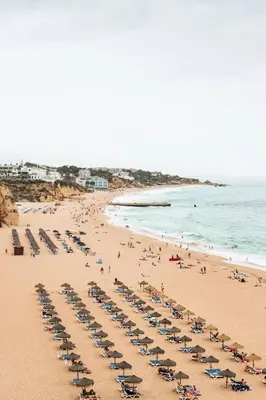 a beach with a lot of chairs and people on it at Casa dos Avós by MTPhomes in Albufeira