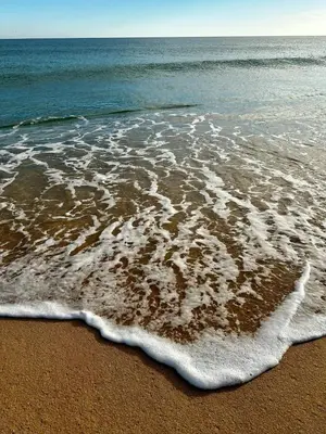 a beach with the foam on the sand and water at Casa dos Avós by MTPhomes in Albufeira