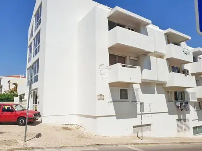 a red car parked in front of a white building at Old Town Apartment 5min to the beach in Albufeira