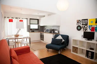 a living room with a orange couch and a kitchen at Acoteias Studio by be@home in Albufeira