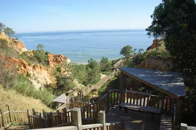 a set of stairs leading down a hill to the ocean at Albufeira 2 bedroom apartment 5 min from Falesia beach and close to center I in Albufeira