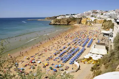 a beach with a lot of people and the ocean at Albufeira 2 bedroom apartment 5 min from Falesia beach and close to center I in Albufeira