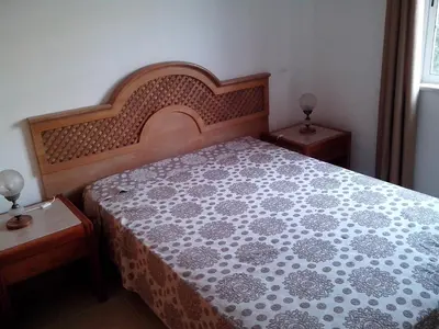 a bedroom with a bed with a wooden headboard and two tables at Albufeira 1 bedroom apartment 5 min from Falesia beach and close to center D in Albufeira