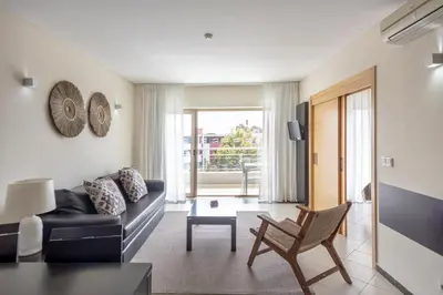 a black leather couch with pillows on a wall at Areias Village Beach Suite Hotel in Albufeira