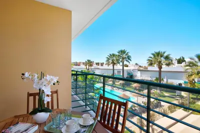a dining room with a view of the pool and palm trees at PALM PARADISE SALGADOS in Albufeira