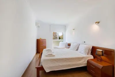 a bedroom with a bed with white sheets and a window at PALM PARADISE SALGADOS in Albufeira