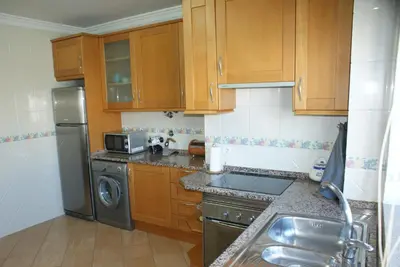 a kitchen with wooden cabinets and a stainless steel refrigerator at Apartamento Felicidade in Almancil