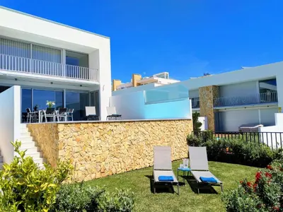 a villa with a stone wall and two chairs at Luxury villa & private heatable pool in Albufeira in Albufeira