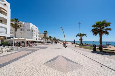 a large white building with people sitting in front of it at Apartamento Zacarias by Ferias com Sol in Quarteira