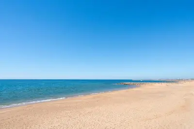 a beach with a bunch of sand and the ocean at Apartamento Zacarias by Ferias com Sol in Quarteira