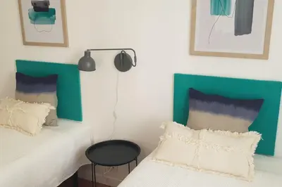 a bedroom with two beds and a black chair at Old Village Design 3 Bedroom Townhouse in Vilamoura