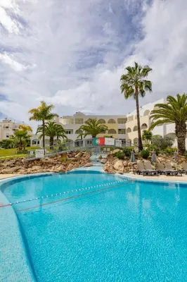 a large swimming pool with palm trees and a resort at Natura Algarve Club in Albufeira