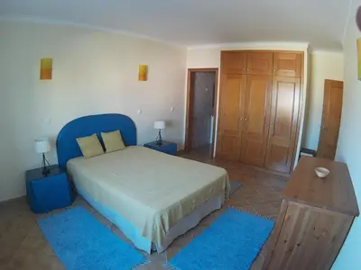 a bedroom with a large bed and blue rugs at AMM Albufeira Nice Hollydays apartment in Albufeira