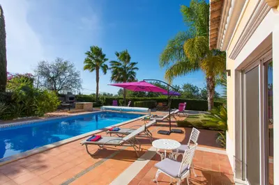 a swimming pool with chairs and a table and umbrella at Casa da Colina in Loulé