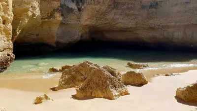 a rock in the sand on a beach next to the water at Magnific Studio with a cozy garden, 5 minutes to the beach in Albufeira