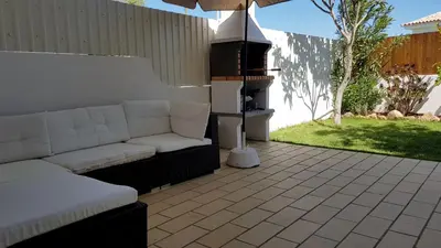 a patio with a couch and an umbrella and a grill at Magnific Studio with a cozy garden, 5 minutes to the beach in Albufeira