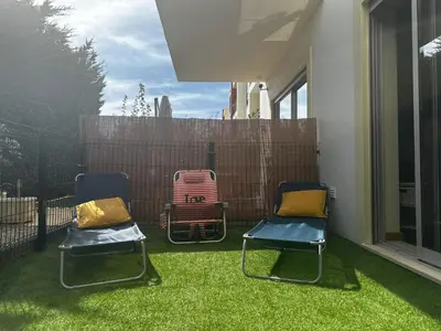 two chairs sitting on a yard with green grass at Condomínio Olhos D'água T1 - Praia, sol e felicidade in Olhos de Água