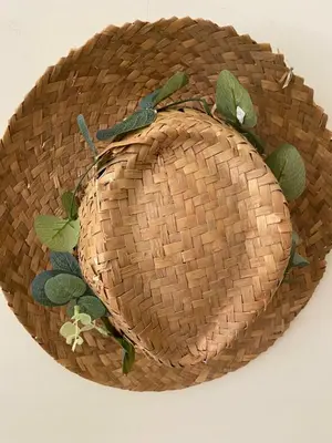 a straw hat with leaves on a white background at Condomínio Olhos D'água T1 - Praia, sol e felicidade in Olhos de Água
