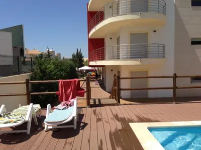 a deck with two lounge chairs and a swimming pool at Condomínio Olhos D'água T1 - Praia, sol e felicidade in Olhos de Água