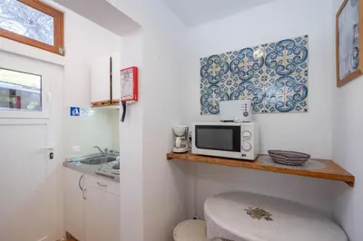a kitchen with white cabinets and a wooden table at Bem Parece by Umbral in Albufeira