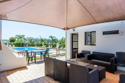 a patio with a table and chairs and a pool at Solgarve in Quarteira