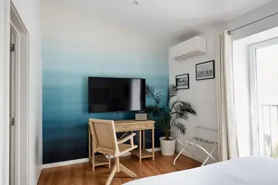 a bedroom with a desk with a tv on a blue wall at Casa Apollo Guesthouse in Faro