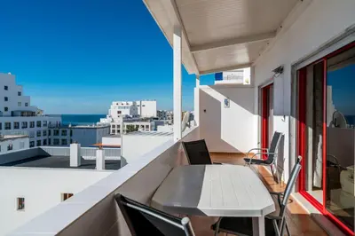 a balcony with a table and chairs and a view of the city at Akisol Quarteira Gun in Quarteira