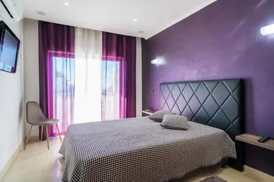 a purple bedroom with a bed and a window at Akisol Quarteira Gun in Quarteira