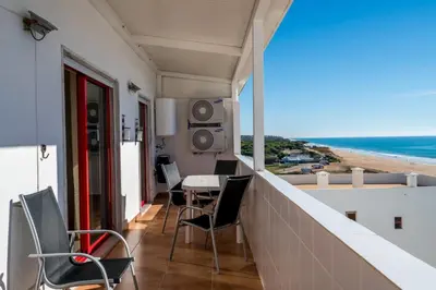 a balcony with a table and chairs and the beach at Akisol Quarteira Gun in Quarteira