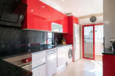 a red kitchen with a sink and a dishwasher at Akisol Quarteira Gun in Quarteira