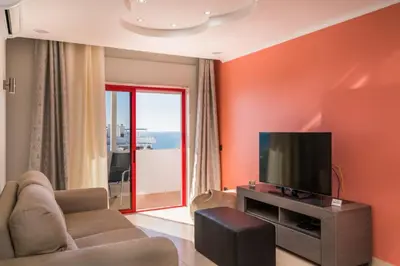 a living room with orange walls and a flat screen tv at Akisol Quarteira Gun in Quarteira