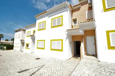 a row of white buildings with yellow windows at 4 bedroom town house Vale de Parra, close to Gale AT22 in Guia