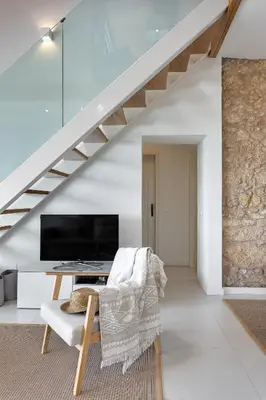 a living room with a staircase with a tv and a chair at Casa Pé na Areia- Unique Spot- Beach front by DreamvillasAlbufeira in Albufeira