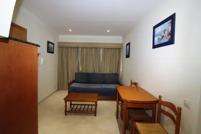 a living room with a blue couch and a table at Beach Waves - Albufeira in Albufeira