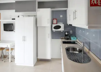 a kitchen with white cabinets and a sink at Comfortable studio in Albufeira - 20 m² - Pleasant balcony in Albufeira