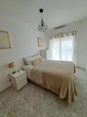 a white bedroom with a large bed and a window at Apartamentos Roja Sol in Albufeira