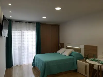 a bedroom with a bed with a green blanket and a window at Lux Home in Albufeira