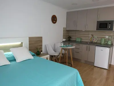 a bedroom with a blue bed and a kitchen at Lux Home in Albufeira