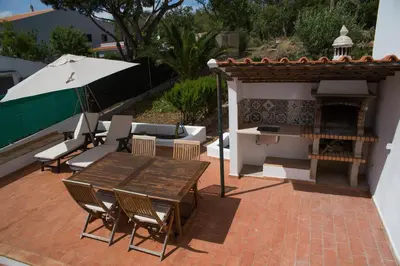 a patio with a table and chairs and an umbrella at CASA GRAZINA in Boliqueime