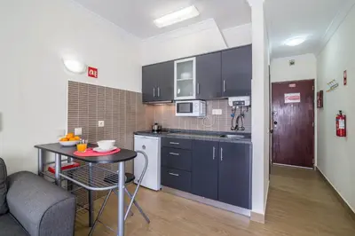 a kitchen with black cabinets and a table in a room at Albufeira Beach Studio in Albufeira