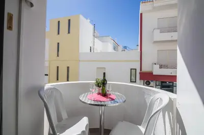 a table with a bottle and two glasses on a balcony at Albufeira Beach Studio in Albufeira