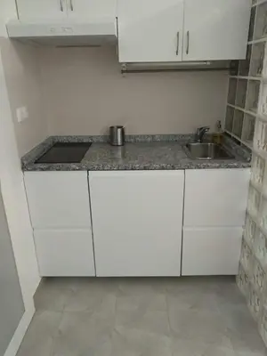 a kitchen with white cabinets and a sink at Estúdio-Gambelas in Faro