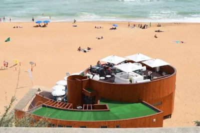 a building on a beach with people on the beach at magnifico apartamento in Albufeira