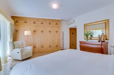 a bedroom with a white bed and a chair at OnJ Vilamoura in Quarteira