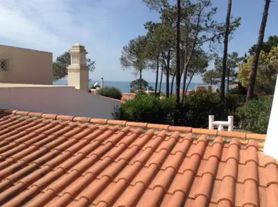 a tile roof of a house with the ocean in the background at Casa Nicho in Vale do Lobo