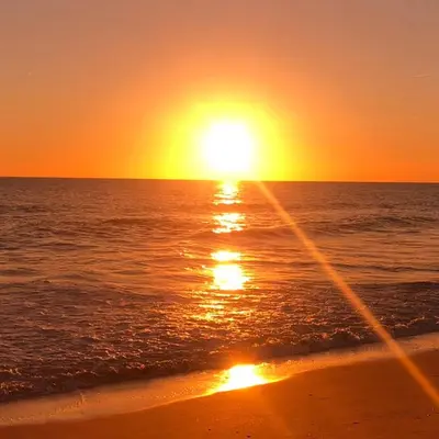 a sunset on the beach with the ocean at Quinta Barracuda Albufeira in Albufeira